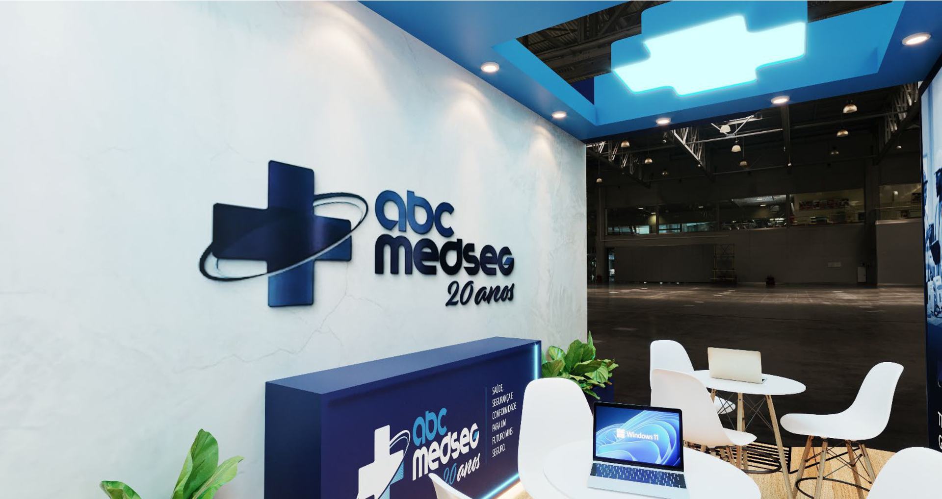 Estande da ABC MedSeg com o logo da empresa na parede e mesas para atendimento